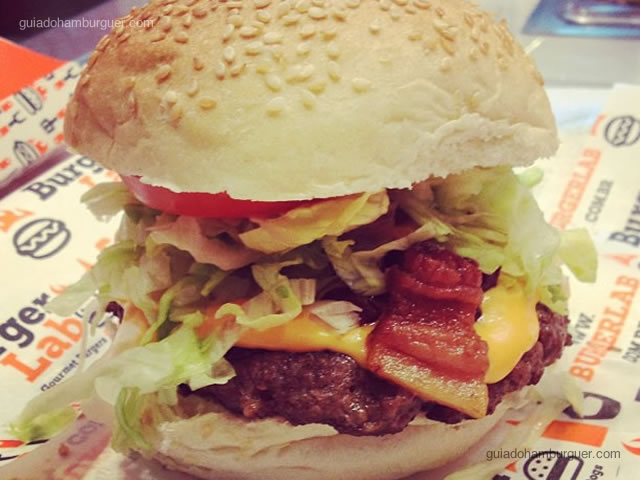 Hambúrguer bovino, queijo cheddar, bacon, alface, tomate e maionese tradicional
