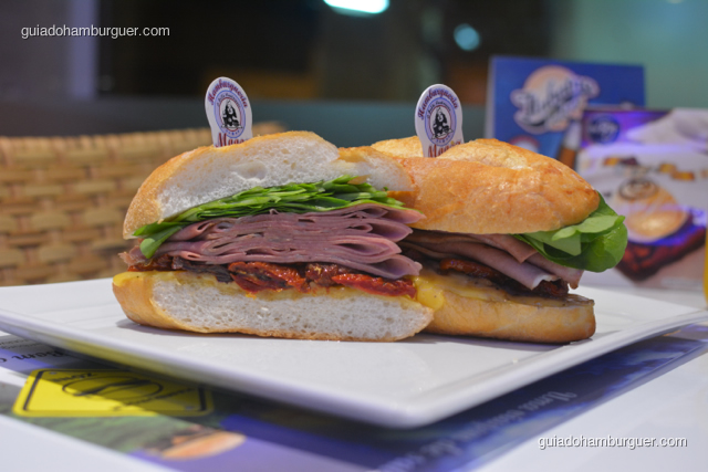 O Imigrante, autêntico lanche de mortadela, servido no pão semi-italiano, mortadela Ceratti puxado na chapa com queijo prato, rúcula e tomate seco - Hamburgueria da Mooca