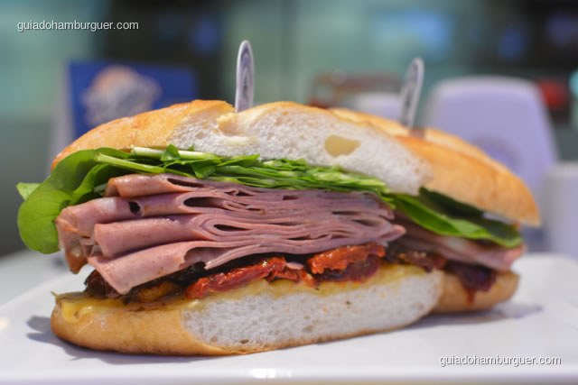 O Imigrante, autêntico lanche de mortadela, servido no pão semi-italiano, mortadela Ceratti puxado na chapa com queijo prato, rúcula e tomate seco - Hamburgueria da Mooca