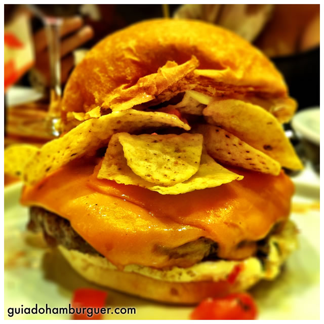 El Nacho: hambúrguer de 150g, servido com queijo cheddar, maionese, pico de gallo, nachos e relish de milho no pão sem gergelim - America