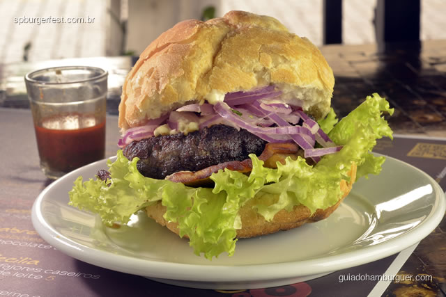Hambúrguer Anticuchero - hambúrguer de carne bovina, com molho aji panca (molho anticuchero), salsa criolla (salada de cebolas roxas com molho de limão e pimenta), batata doce, alface e maionese, servido com molho a parte de pimenta vermelha e huacatay. - SP Burger Fest 3ª edição