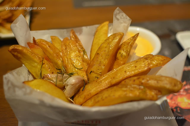 Batatas rústicas acompanhadas de uma porção de queijo cheddar cremoso - Paulista Burger