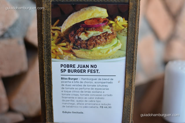 Blis Burger: hambúrguer de blend de picanha e bife de chorizo, acompanhado de duas versões de tomate (chutney de tomate ao perfume de especiarias e toque cítrico de limão siciliano e tomate crispy, tomate concassé cortado finamente e seco ao calor indireto da parrilla). Queijo de cabra tipo manchego, alface americana e redução de balsâmico no pão ciabata  - Pobre Juan