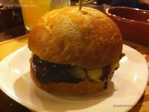 Santo Hambúrguer com hambúrguer de picanha, queijo ementhal, confit de cebola, maionese e molho barbecue no pão caseiro rústico